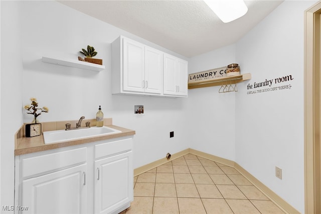 clothes washing area with light tile patterned floors, cabinet space, a sink, washer hookup, and a textured ceiling