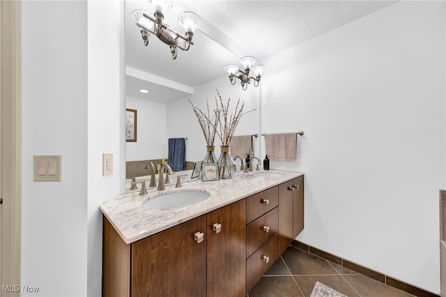 full bath with tile patterned floors, double vanity, an inviting chandelier, and a sink