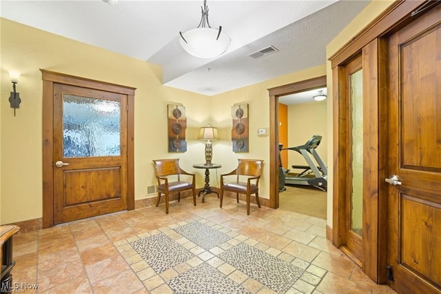 foyer featuring baseboards, visible vents, and stone finish flooring