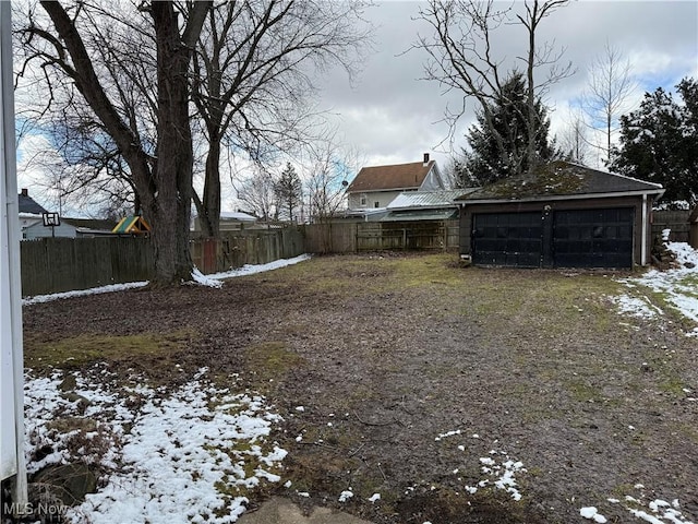 yard layered in snow with fence and a detached garage