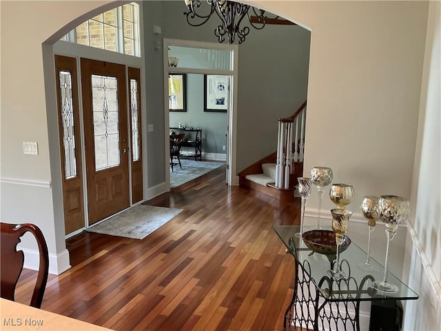 entryway with baseboards, stairway, wood-type flooring, and a notable chandelier