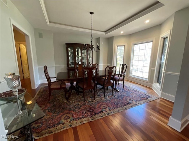 dining area featuring a tray ceiling, visible vents, an inviting chandelier, and wood finished floors