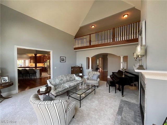 living room with light carpet, high vaulted ceiling, arched walkways, and ornate columns