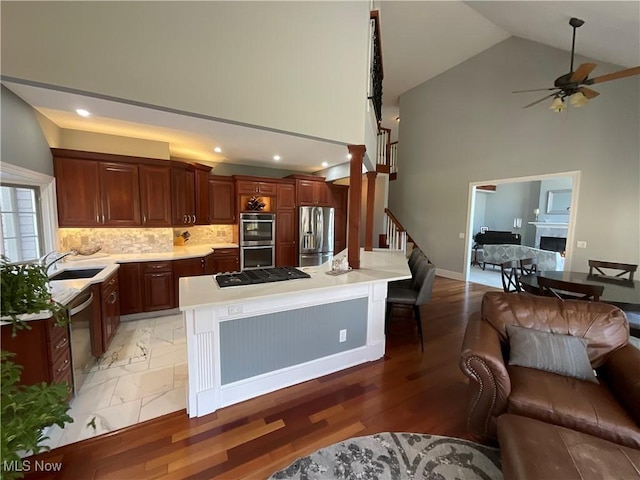 kitchen with a fireplace, stainless steel appliances, light countertops, decorative backsplash, and open floor plan