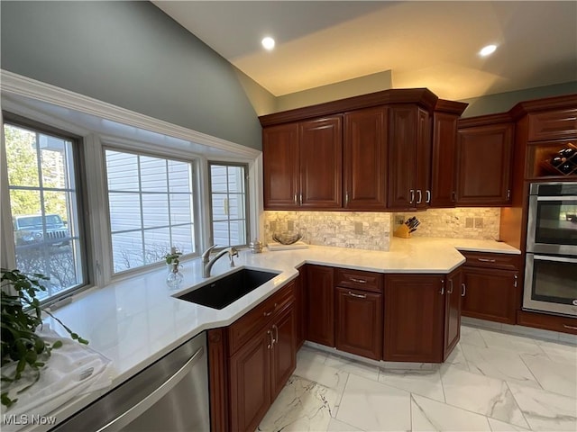 kitchen with appliances with stainless steel finishes, marble finish floor, light countertops, and a sink