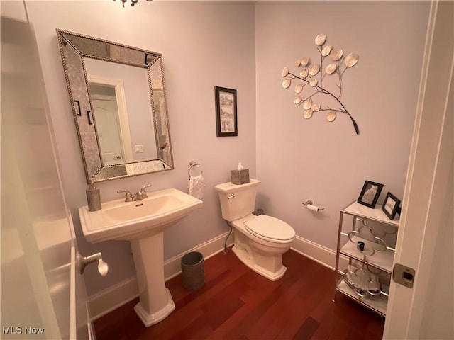 half bathroom with toilet, baseboards, and wood finished floors