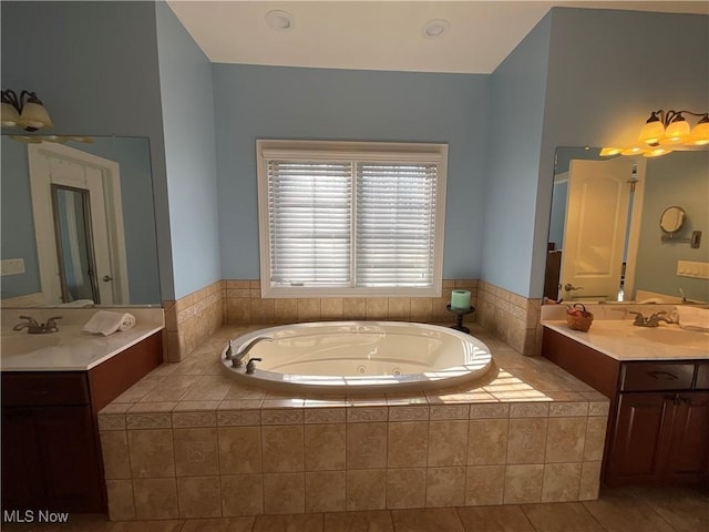 bathroom with a jetted tub, two vanities, a sink, and tile patterned floors