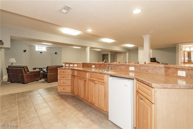 kitchen featuring open floor plan, white dishwasher, light countertops, light brown cabinetry, and a sink