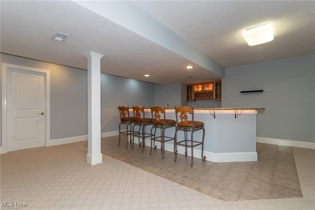 kitchen with recessed lighting, visible vents, baseboards, a kitchen bar, and glass insert cabinets