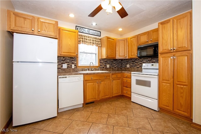 kitchen with dark countertops, white appliances, tasteful backsplash, and a sink