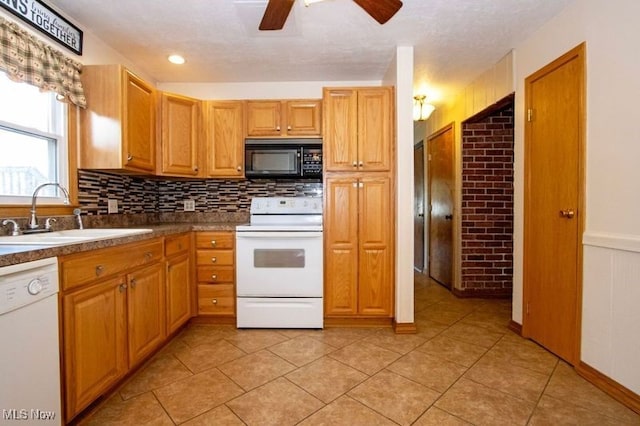 kitchen featuring white appliances, tasteful backsplash, a wainscoted wall, ceiling fan, and a sink