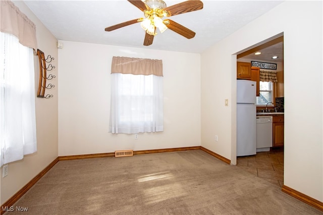 spare room with light carpet, plenty of natural light, a sink, and visible vents