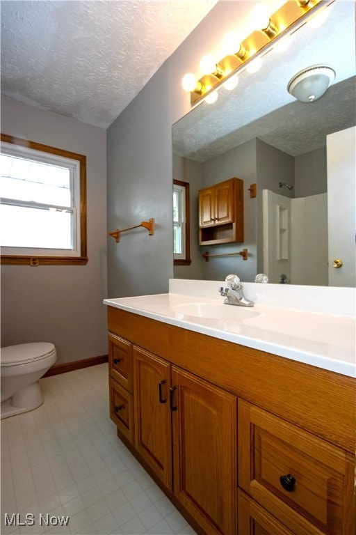 bathroom featuring toilet, baseboards, a textured ceiling, and vanity