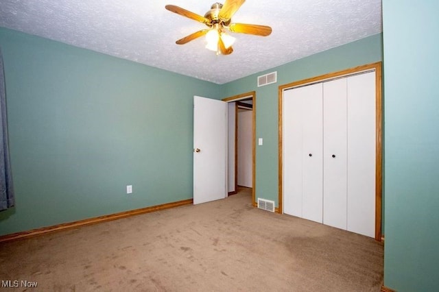 unfurnished bedroom with a closet, visible vents, a textured ceiling, and carpet flooring