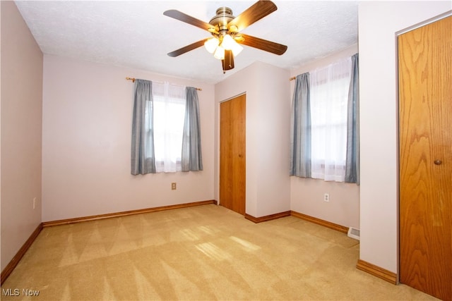 unfurnished bedroom featuring a textured ceiling, carpet flooring, a ceiling fan, visible vents, and baseboards