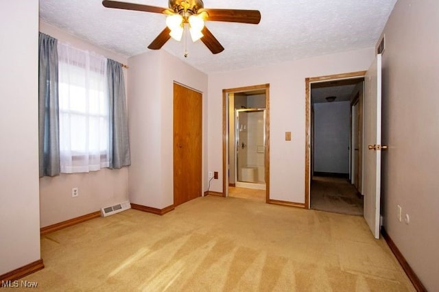 unfurnished bedroom with a textured ceiling, light carpet, and baseboards