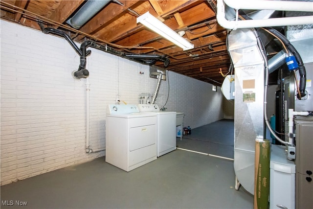 unfinished below grade area featuring heating unit, brick wall, and separate washer and dryer