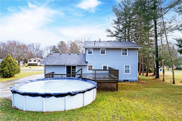 back of property featuring crawl space, a covered pool, a lawn, and a wooden deck