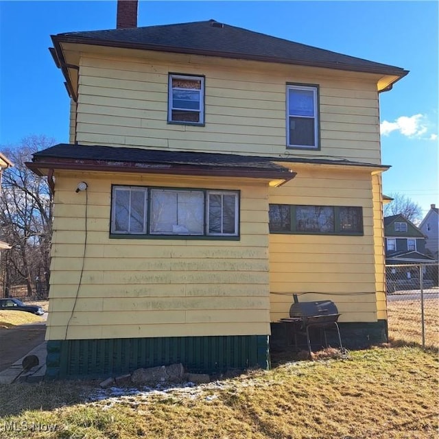 view of side of home with fence and a chimney