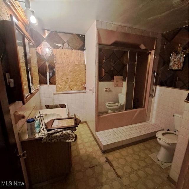 full bath with an enclosed shower, tile walls, toilet, and vanity