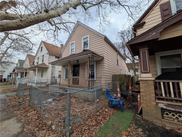 view of side of property featuring a fenced front yard, a residential view, and a porch