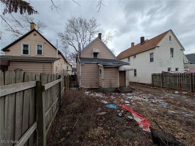 rear view of house featuring entry steps, an outdoor structure, and a fenced backyard