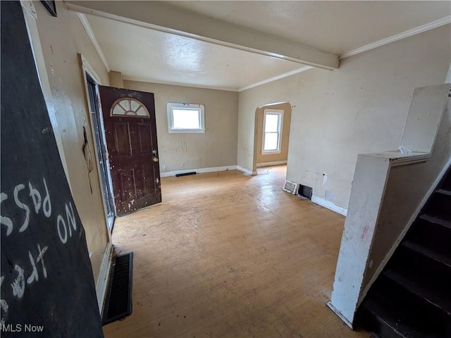 foyer entrance featuring arched walkways, ornamental molding, wood finished floors, and baseboards