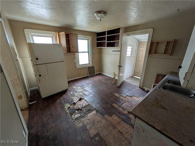 kitchen featuring a sink, open shelves, dark wood-style flooring, and freestanding refrigerator