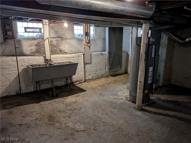 basement with water heater, a sink, and a healthy amount of sunlight