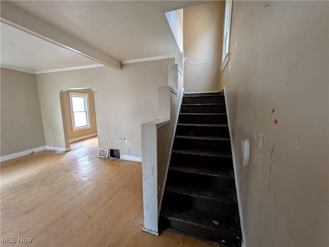 stairs with arched walkways, beam ceiling, baseboards, and wood finished floors