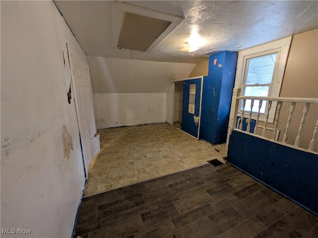 bonus room with vaulted ceiling, a textured ceiling, and tile patterned floors