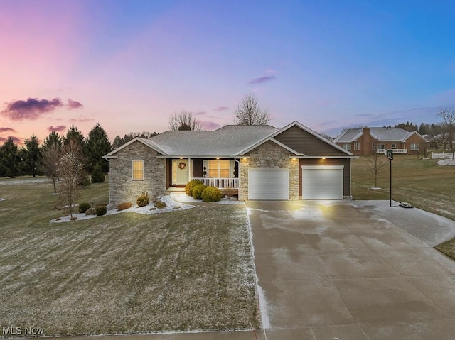 view of front of home with covered porch, an attached garage, stone siding, driveway, and a front lawn