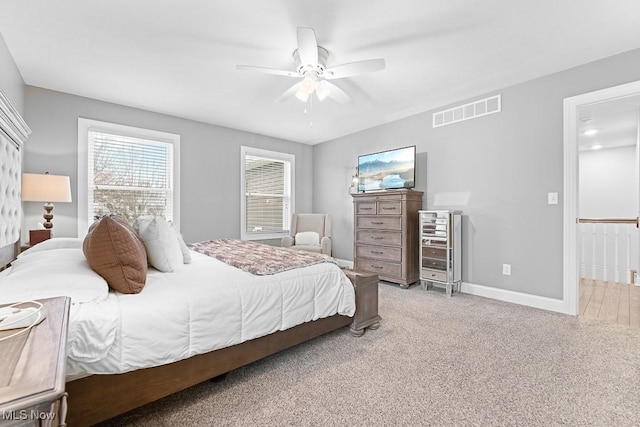 bedroom with a ceiling fan, light colored carpet, visible vents, and baseboards