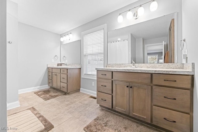 bathroom featuring two vanities, a sink, visible vents, and baseboards