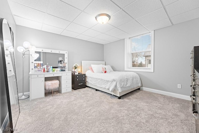 carpeted bedroom featuring a paneled ceiling and baseboards