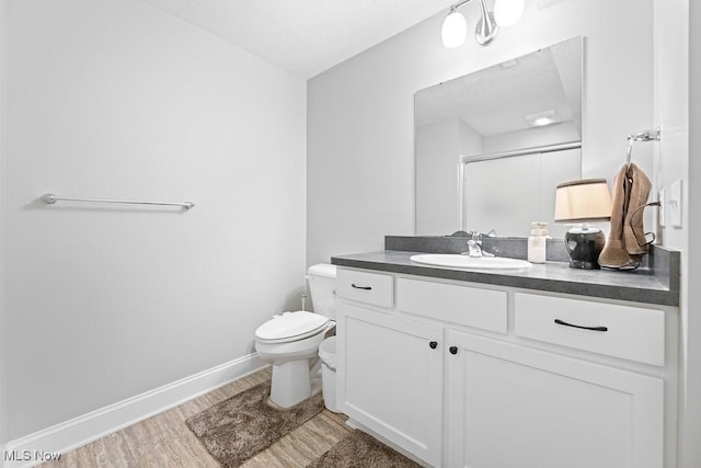 full bathroom with baseboards, toilet, wood finished floors, vanity, and a shower stall