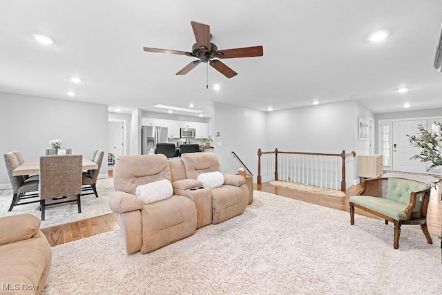 living area with light wood-style floors, ceiling fan, baseboards, and recessed lighting