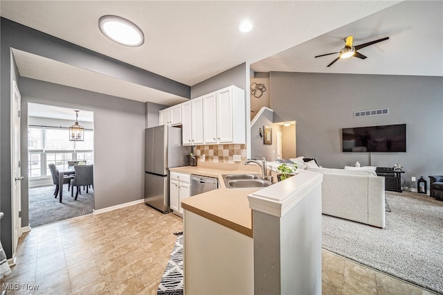 kitchen with a sink, visible vents, white cabinetry, vaulted ceiling, and appliances with stainless steel finishes