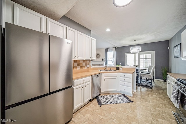 kitchen featuring a peninsula, appliances with stainless steel finishes, wood counters, and white cabinets