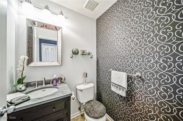 bathroom with toilet, visible vents, a textured ceiling, and vanity