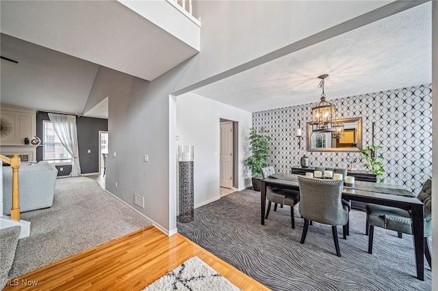 dining area with an inviting chandelier, a textured ceiling, wood finished floors, baseboards, and wallpapered walls