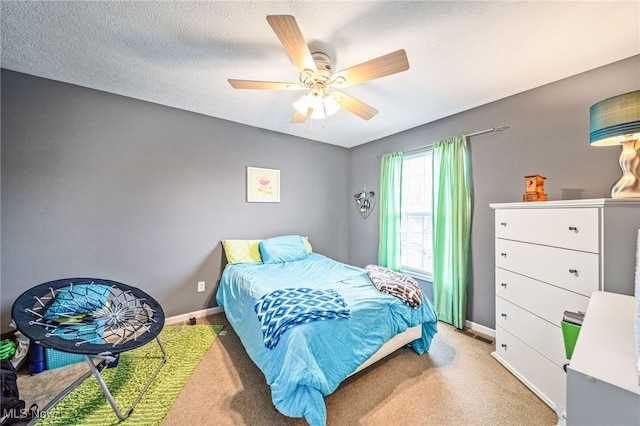 bedroom featuring ceiling fan, a textured ceiling, baseboards, and carpet flooring