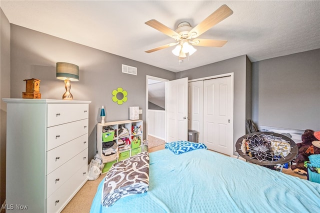 bedroom featuring a closet, visible vents, a ceiling fan, and light colored carpet