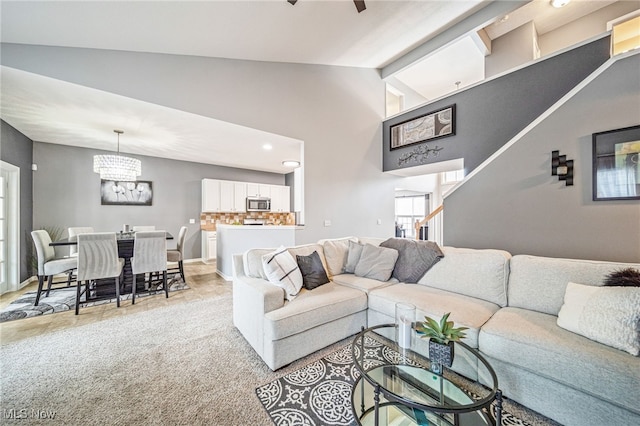 living area with a chandelier, high vaulted ceiling, light colored carpet, baseboards, and stairs