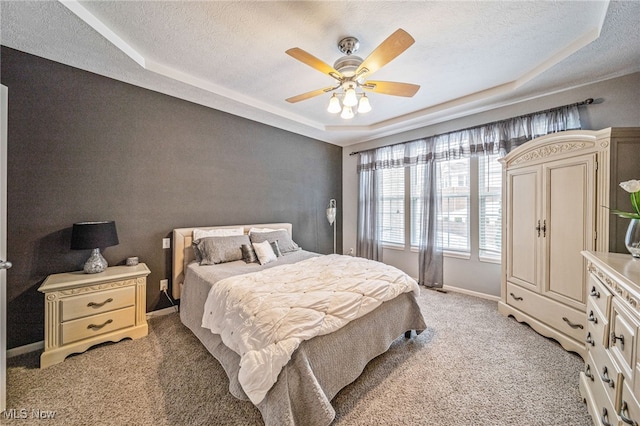 bedroom featuring a raised ceiling, ceiling fan, a textured ceiling, and baseboards