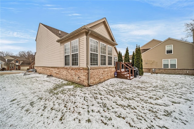 snow covered property with brick siding