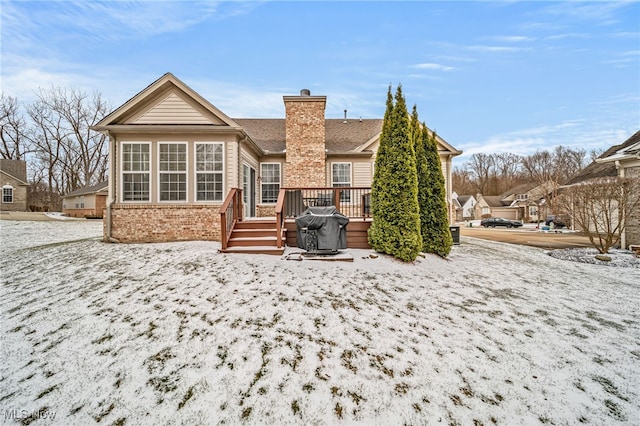 back of house with a deck, brick siding, and a chimney