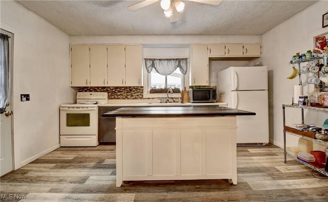 kitchen with a sink, white appliances, a textured ceiling, and wood finished floors