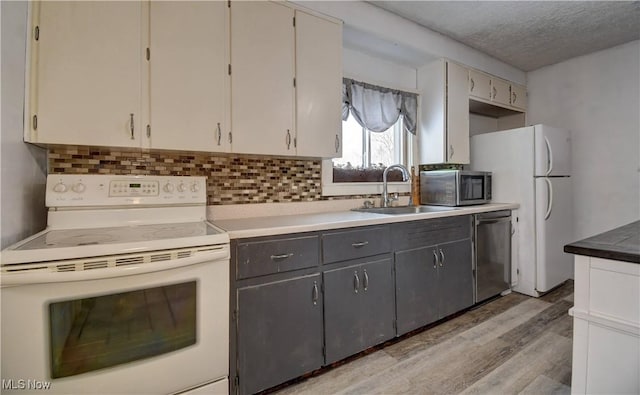 kitchen featuring stainless steel appliances, backsplash, a sink, and light wood-style flooring