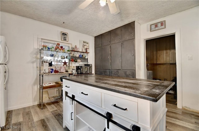 kitchen featuring dark countertops, light wood-style flooring, and a textured ceiling